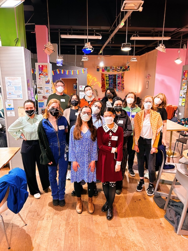 13 people in a fun welcoming space wearing masks, many with cute mask chains