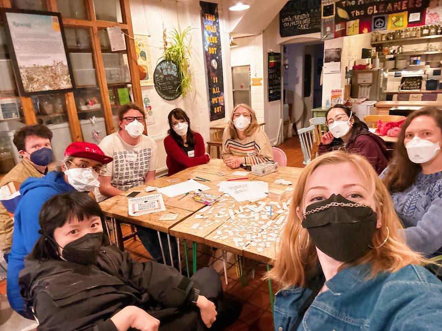 9 people in masks around a table with games and crafts at The Hornbeam Centre